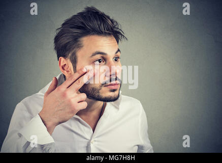 Young man pulling down eyelid checking his eye looking in mirrow feels unwell has black circles Stock Photo