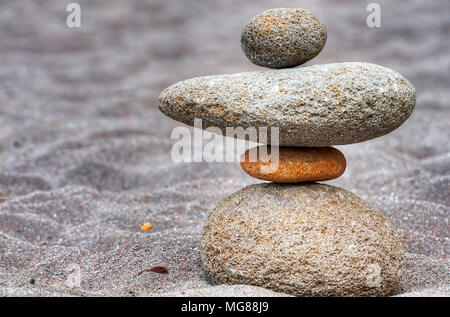 Stacks of river rocks resembling people along a sandy beach of the Sandy River in Oregon.  Many are grouped into little families, solidarity figures t Stock Photo
