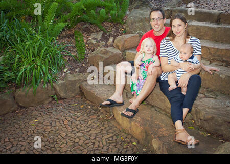 Family of four sitting on steps Stock Photo