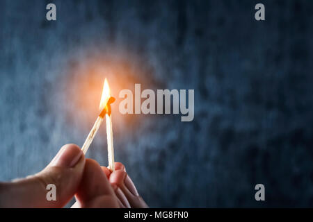 One match sets the other on fire. Fire from matches on a dark blue background. The concept of support, leadership. Photo with copy space. Stock Photo