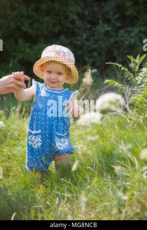 A sweet little baby girl learning to walk in summer Stock Photo
