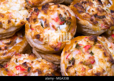 Portioned round mini pie made of crispy puff pastry stuffed with green onion eggs and crab meat and cheese baked in the oven and stacked on a platter  Stock Photo