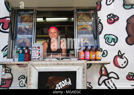Portrait of a Hispanic female small business owner posing in the window of her sandwich food truck Stock Photo