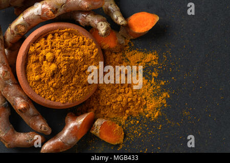turmeric powder with turmeric root on black table, spices and herb concept Stock Photo