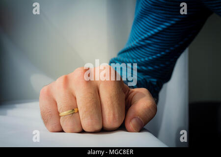 Man with a wedding ring squeezed his hand on white cloth background. Stock Photo