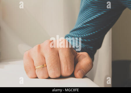 Man with a wedding ring squeezed his hand on white cloth background. Stock Photo
