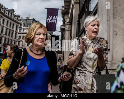 Two women walking along street, in a hurry, with startled expressions, London, England, UK Stock Photo