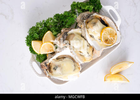 Fresh opened oysters on a white plate. Selective focus Stock Photo