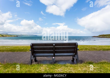 Co. Antrim/N. Ireland - May 31, 2015: A lone bench sits overlooking the scenic Browns Bay in Co. Antrim, N. Ireland on a partly sunny day. Stock Photo