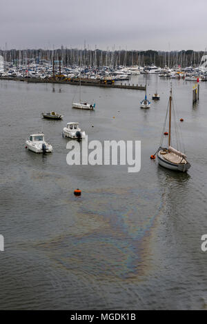 Oil pollution on the surface of the water or sea on the lymington river in the new forest in Hampshire. Oil spillages into sea environmental damaging. Stock Photo