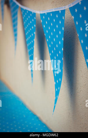 line of colorful blue party decorations flags with white stars illustration hanging from the wall. Stock Photo