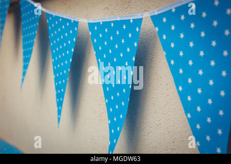 line of colorful blue party decorations flags with white stars illustration hanging from the wall. Stock Photo