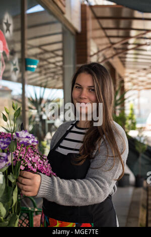 Smiling female florist wearing black apron. Vertical composition. Stock Photo