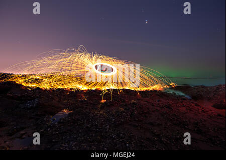 Showers of hot glowing sparks from spinning steel wool on the beach Stock Photo