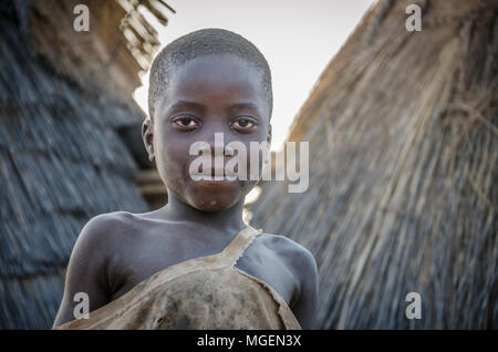 Boy of the Tata Somba tribe or Tammari people with torn clothes standing on roof of mud building Stock Photo