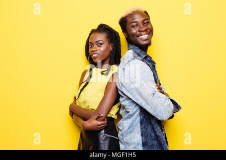 Portrait of afro american couple standing back to back isolated over yellow Stock Photo