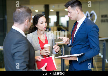 Serious confident mixed race lady proving her opinion while talking to young entrepreneurs after business conference Stock Photo