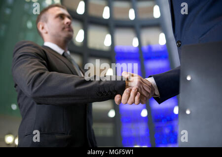 Close-up of serious confident businessman making handshake with new business partner in office hall Stock Photo