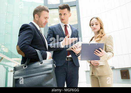 Serious confident young male manager offering strategy for business development while sharing it with boss in office, female business assistant showin Stock Photo