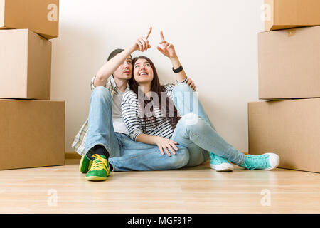 Photo of man and woman sitting on floor among cardboard boxes Stock Photo