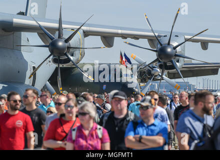 28 April 2018, Germany, Schoenefeld: Many visitors walking through the grounds of the ILA 2018. The propellers of the Bundeswehr transport aircraft Airbus A400M can be seen in the foreground while a Transall C-160D can be seen in the background. About 200 aircraft are being presented during the ILA 2018 international aeronautic exhibition. The organisers expect about 150,000 visitors. The ILA takes place between 25 and 29 April 2018. Photo: Patrick Pleul/dpa-Zentralbild/dpa Stock Photo