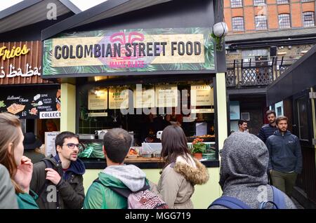 street style food stalls at kerb camden market the stables london UK selling hotdogs fish and chips curries colombian indian and more with tourists Stock Photo