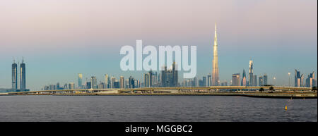 Panoramic view of Dubai skyline at dawn, with the Burj Khalifa catching the first light of the sun, showcasing the UAE's iconic architectural marvel Stock Photo