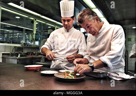 Three-starred chef Régis Marcon (right) at work with his son Jacques (left) in the kitchen of his restaurant in Saint-Bonnet-le-Froid, France Stock Photo