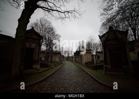 Pathway / Road going through Père Llachaise Cemetery in Paris with lots of tombs and gravestones Stock Photo