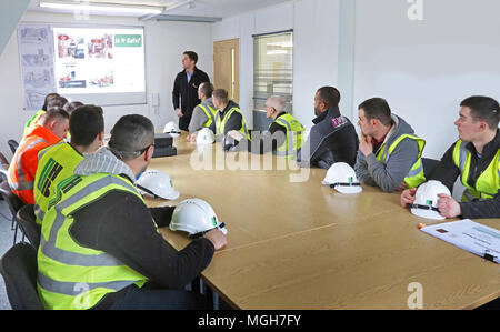 A construction site health and safety briefing takes place in in London site office. Site workers attend with their hard hats on the table. Stock Photo