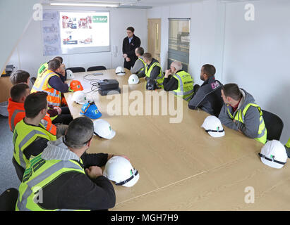 A construction site health and safety briefing takes place in in London site office. Site workers attend with their hard hats on the table. Stock Photo