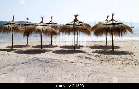 Porto Pollenca, Mallorca, Spain. 2018. Thatched sunshades on the beach in the early morning light. Stock Photo