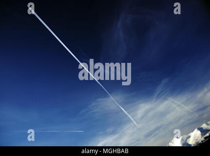 High altitude jet contrails on a dark blue sky Stock Photo