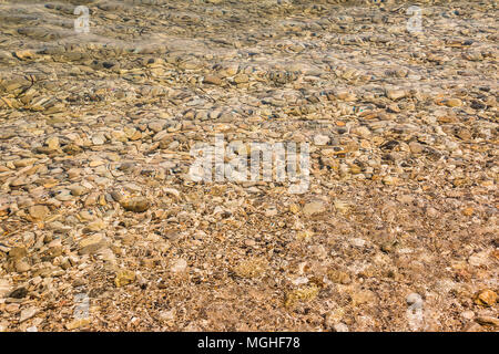 Pebble beach with azure sea water texture background.Stone pattern under the water in a beautiful sunny summer day. Stock Photo