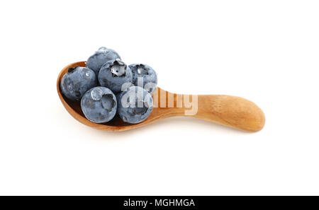 Close up several fresh washed blueberry berries with water drops in one rustic natural wooden scoop spoon isolated on white background, high angle vie Stock Photo