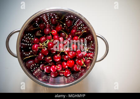 Fresh red cherries being washed in colander.organic red sweet cherries in steel colander on white background.Healthy food concept. Stock Photo