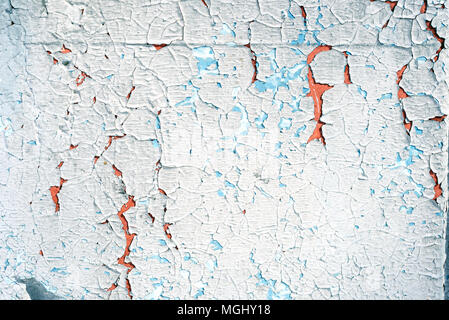 Old flaking blue paint with an orange vibrant undercoat showing up through cracked broken plaster with a copyspace area for DIY reconstruction and bui Stock Photo