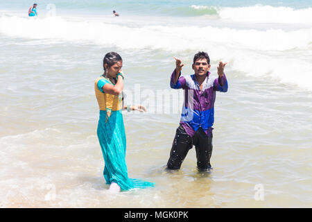 MASI MAGAM FESTIVAL, PUDUCHERY, PONDICHERY, TAMIL NADU, INDIA - March 1, 2018. Unidentified Indian pilgrims young couple bathing, in the sea, on the b Stock Photo
