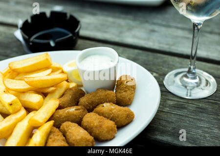 a plate of scampi and chips on a wooden table Stock Photo