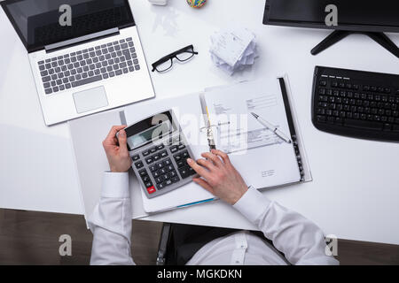 Elevated View Of A Businessperson's Hand Calculating Invoice With Calculator Stock Photo