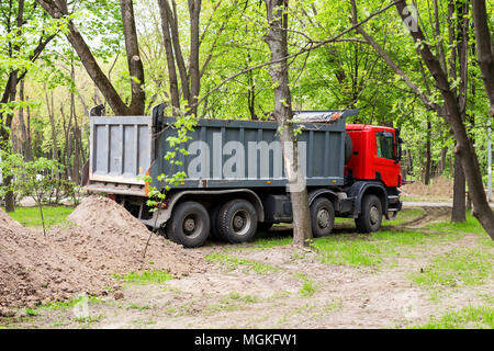 White dump truck dumping sand and soil material at an outdoor ...