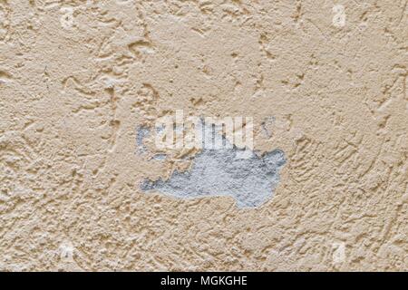 A damaged house wall and flaked exterior plaster with a large hole Stock Photo
