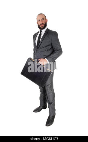 A young handsome business man standing in profile and holding his black briefcase, isolated over white background Stock Photo