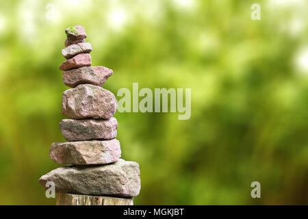 Stacked stone pyramid in front of green blurry background Stock Photo