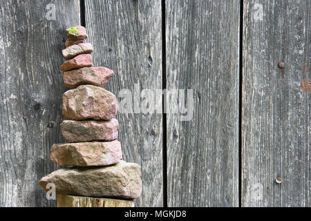 Stacked stone pyramid in front of a wooden wall Stock Photo