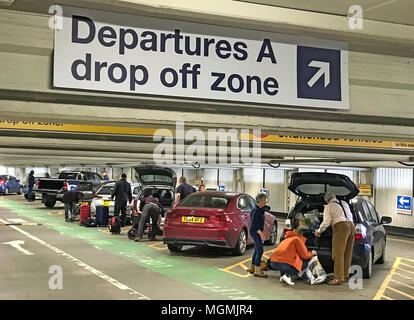 Manchester International Airport Passengers unload cars in an airport departures drop-off zone as average charges at major UK airports rise by a third Stock Photo