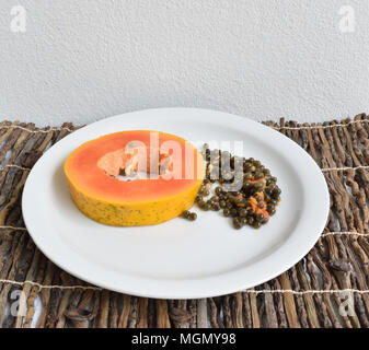 Slice of ripe papaya with seeds on a ceramic plate Stock Photo