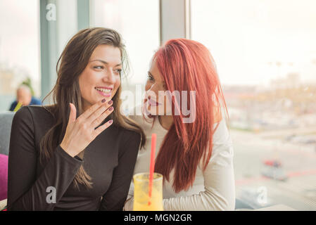 Portrait of two young beautiful women at coffee shop, girl talk. Two female friends enjoying together in a restaurant laughing, talking and gossiping. Stock Photo