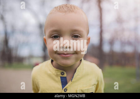 Adorable little boy having fun on playground. Active sport leisure for kids outdoor in park. Little boy with blue eyes in yellow shirt playing and hav Stock Photo