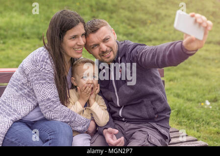 Parents having fun with their child in park. Beautiful family is having fun outside. Mom with dad are playing with their little son on playground. Stock Photo